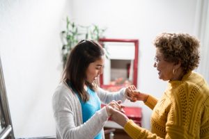 A woman experiencing fatigue, muscle stiffness, and mobility limitations in MS holds the hands of her caregiver.