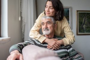A woman considers adding home care in assisted living as she hugs her father.