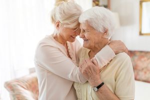 Family caregiver hugging happy senior woman