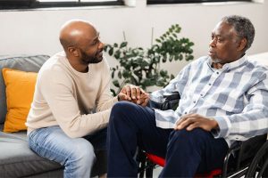 A man holds the hand of his father as he considers how to reduce dementia environmental triggers.