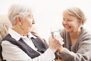 Family caregiver handing a glass of water to senior loved one