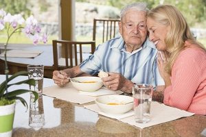 senior man with caregiver eating breakfast
