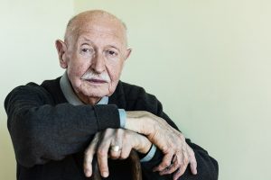 A man whose family is focused on preserving a loved one’s independence leans confidently on his cane.