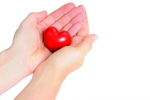 Hands hold a red heart, symbolizing taking care of your heart by watching for the signs of a CHF flareup.