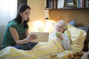 Caregiver discusses care plan with senior woman in bed
