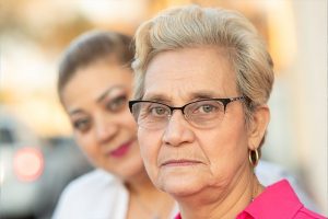 A woman stares into the camera wondering how to support family caregivers.