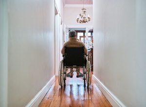 senior in a wheelchair rolling down the hallway in their own home