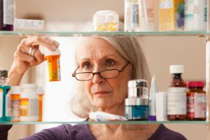 senior-lady-looking-at-medication-in-medicine-cabinet