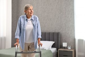A woman leans on her walker as she goes through hip replacement recovery at home.
