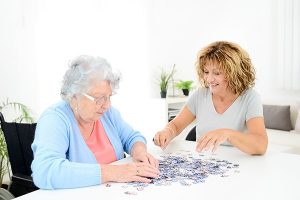 senior-woman-and-caregiver-putting-puzzle-together