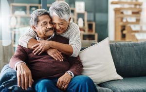 Senior woman hugging husband on the couch