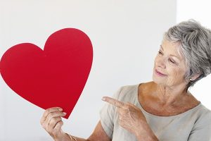 Senior woman pointing to a red paper heart